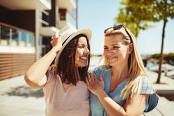 Two female friends walking along the river on a sunny day