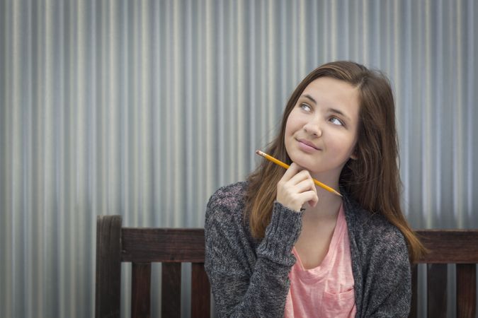 Young Daydreaming Female Student With Pencil Looking to the Side