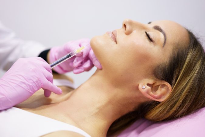 Woman having fillers injected into chin
