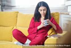 Woman sipping tea on yellow sofa at home 5rQ9n0