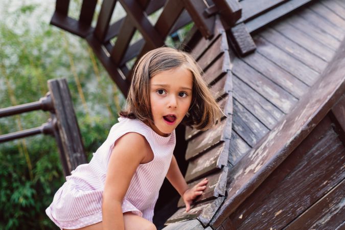 Smiling girl climbing onto wooden playground