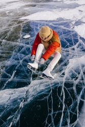 Woman sitting on frozen river and tying the shoelaces