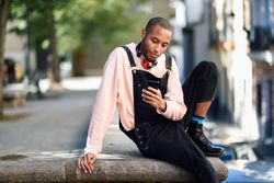 Calm male sitting in city checking phone