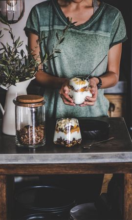 Woman holding yogurt parfait on rustic table
