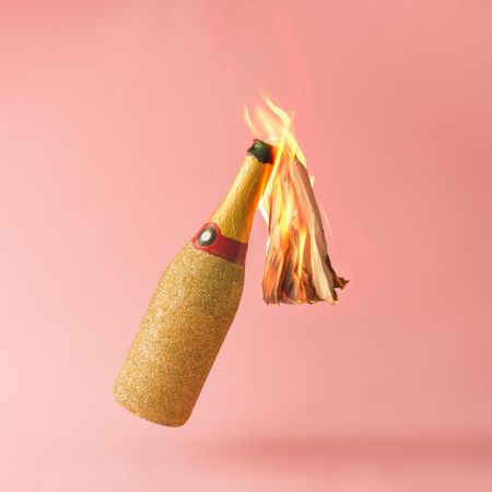 Molotov cocktail gold champagne bottle on pink background
