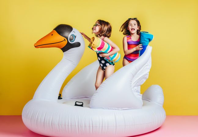 Young girls in swimwear playing on inflatable mattress