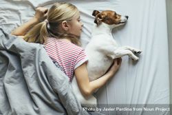 Young girl cuddling with her dog in bed, top view 0JGBd5