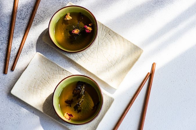 Top view of two cups of green tea and chopsticks