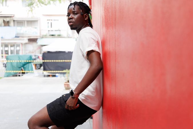 Black male leaning on red wall