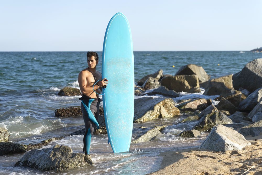 Male surfer standing in the rocks on the coast