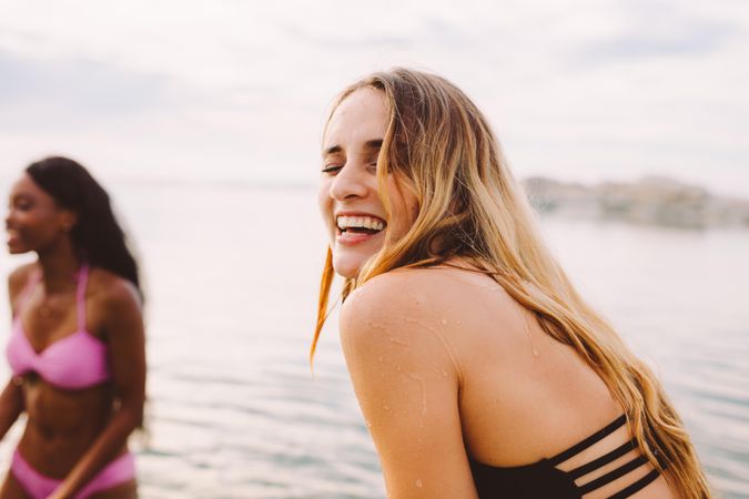 Woman laughing at the beach with friend in the background