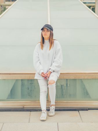 Young woman with glasses standing against wall