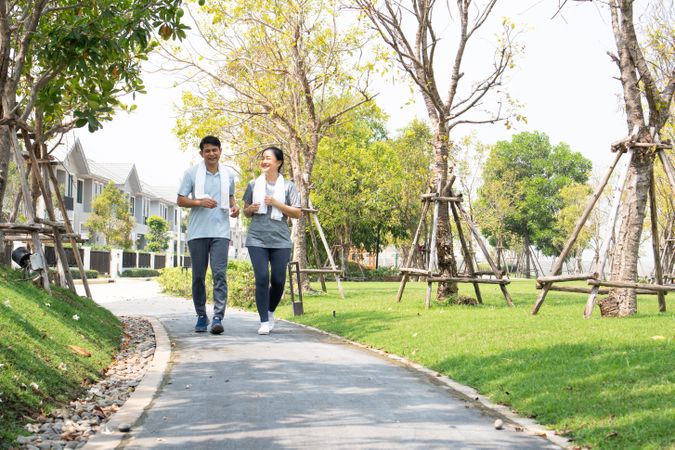 Smiling male and female jogging on walkway