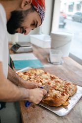 Arabic pizza maker cutting dough with cutter