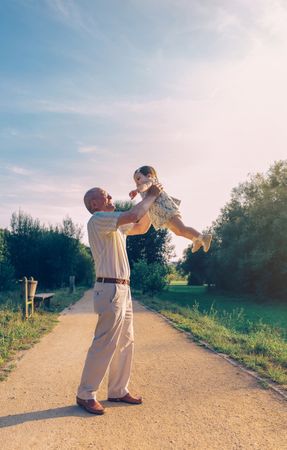 Man playing with baby girl outdoors on path in park