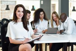 Brunette businesswoman smiling in office looking at camera