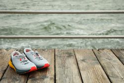 Sneakers on wooden floor outdoors, space for text