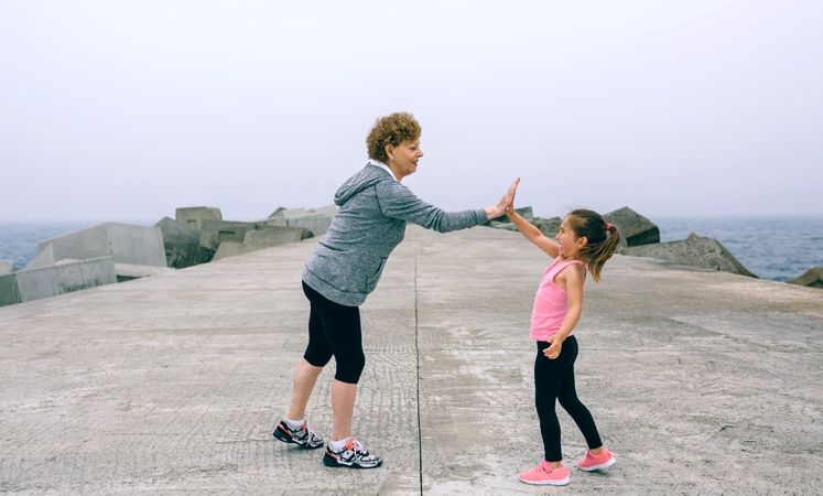 Mature sportswoman and little girl high five
