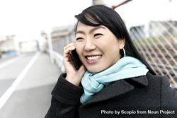 Smiling East Asian woman having a phone call outdoor 0VJDk0