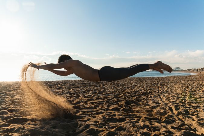 Sporty man levitating over sand during workout