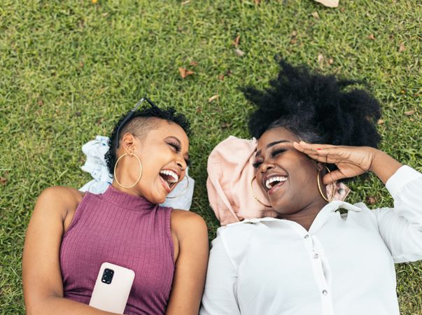 Happy women taking selfies lying on the grass