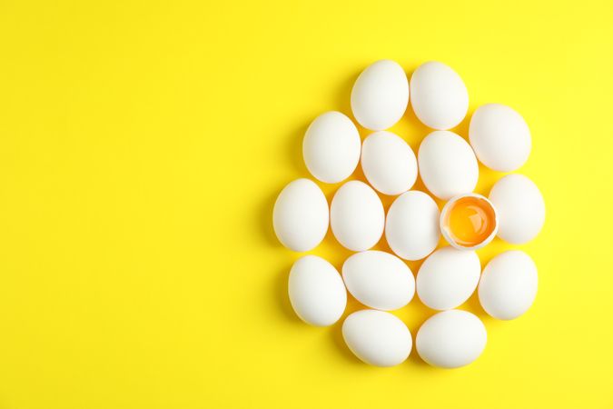 Flat lay composition with chicken eggs and half with yolk on color background, space for text