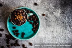 Top view of coffee beans in teal cup with star anise 56YMl0