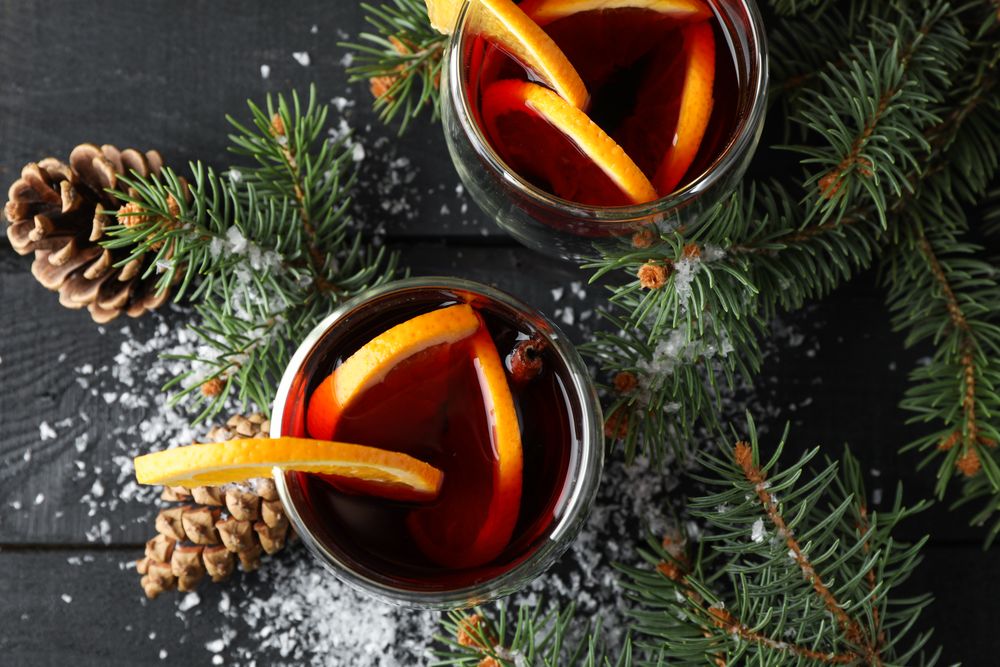 Glasses of tasty mulled with orange on decorated background, top view