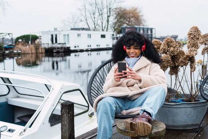 Cheerful Black woman listening to music at lakeside