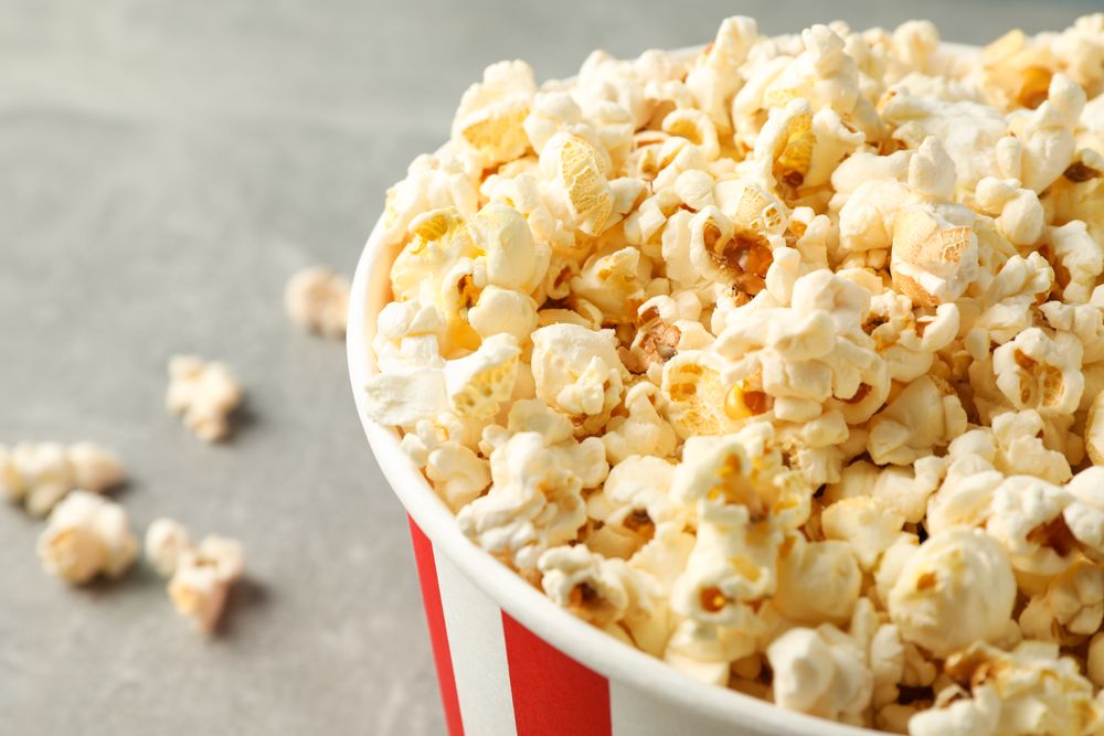 Bucket with popcorn on grey background, space for text