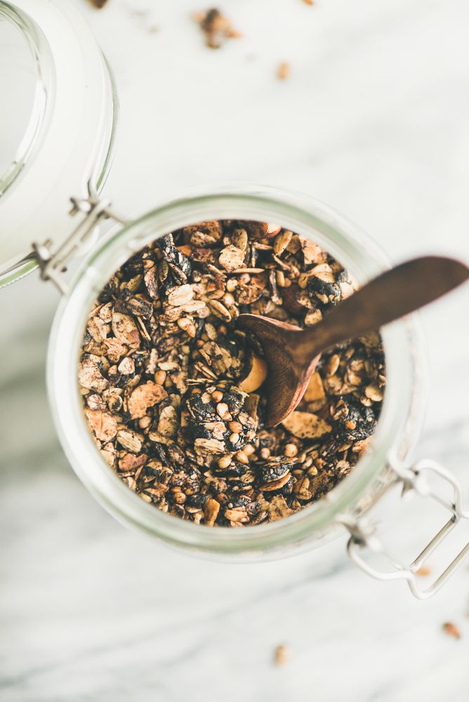 Top view glass container of homemade granola, close up, with copy space