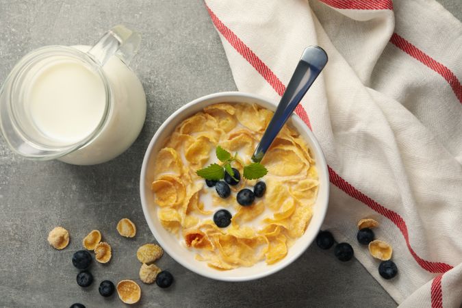 Concept of breakfast with muesli, milk and blueberry on gray table