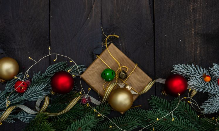 Top view of Christmas gift wrapped in brown paper surrounded by baubles and lights