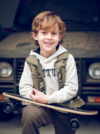 Smiling kid with skateboard on street