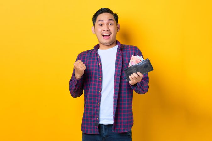 Thrilled man holding wallet with cash