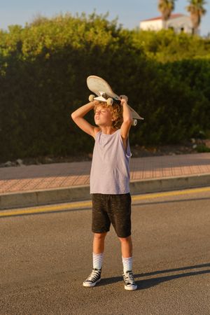 Boy standing with skateboard on road