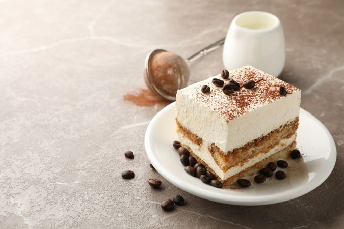 Composition with plate of tiramisu on light brown background. Tasty dessert