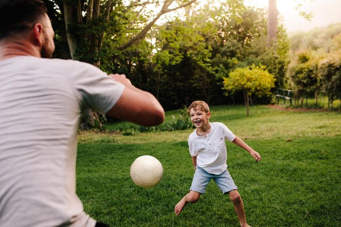 Father and son playing football in backyard garden