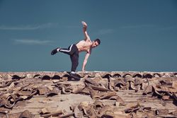 Athletic man performing handstand rotation while dancing breakdance on roof