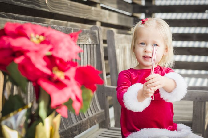 Adorable Little Girl Sitting On Bench with Her Candy Cane