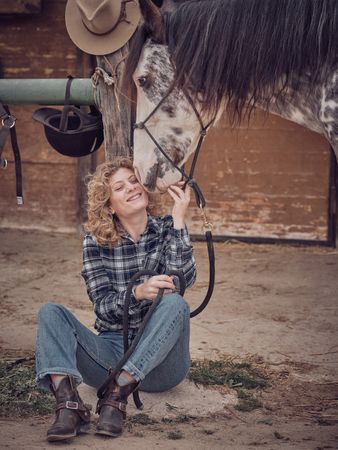 Cheerful woman caressing horse in paddock