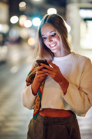 Chic woman with scarf in hair smiling down at her phone