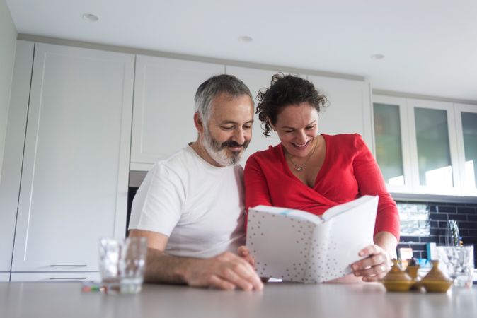 Smiling couple deciding on recipes in bright kitchen