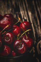 Juicy red cherry in bowl on rustic surface