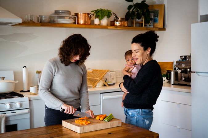Female couple and baby in kitchen preparing lunch
