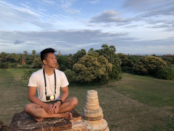 Man in light shirt with a camera sitting outdoor in nature