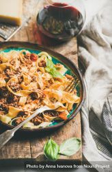 Pasta dinner with minced meat, cheese and red wine on wooden board, close up 56NZP5