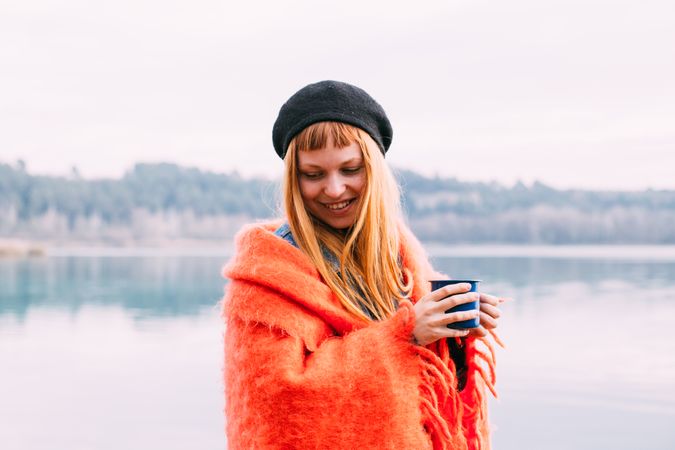 Woman smiling with coffee cup with lake in the background