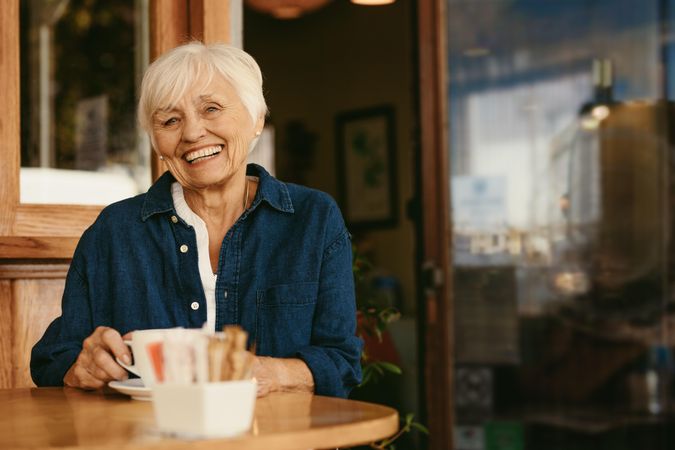 Portrait of smiling woman sitting at cafe with cup of coffee on table