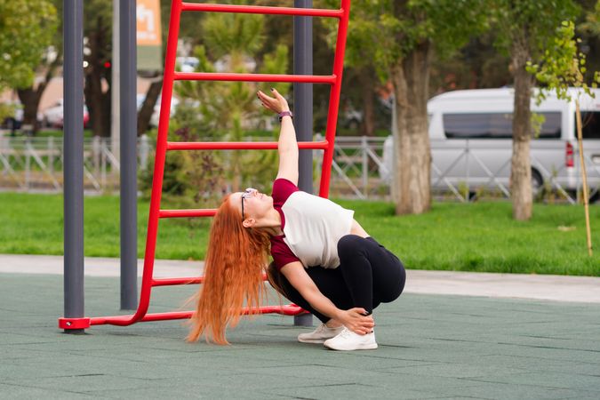 Woman stretching upward while squatting during outdoor exercise